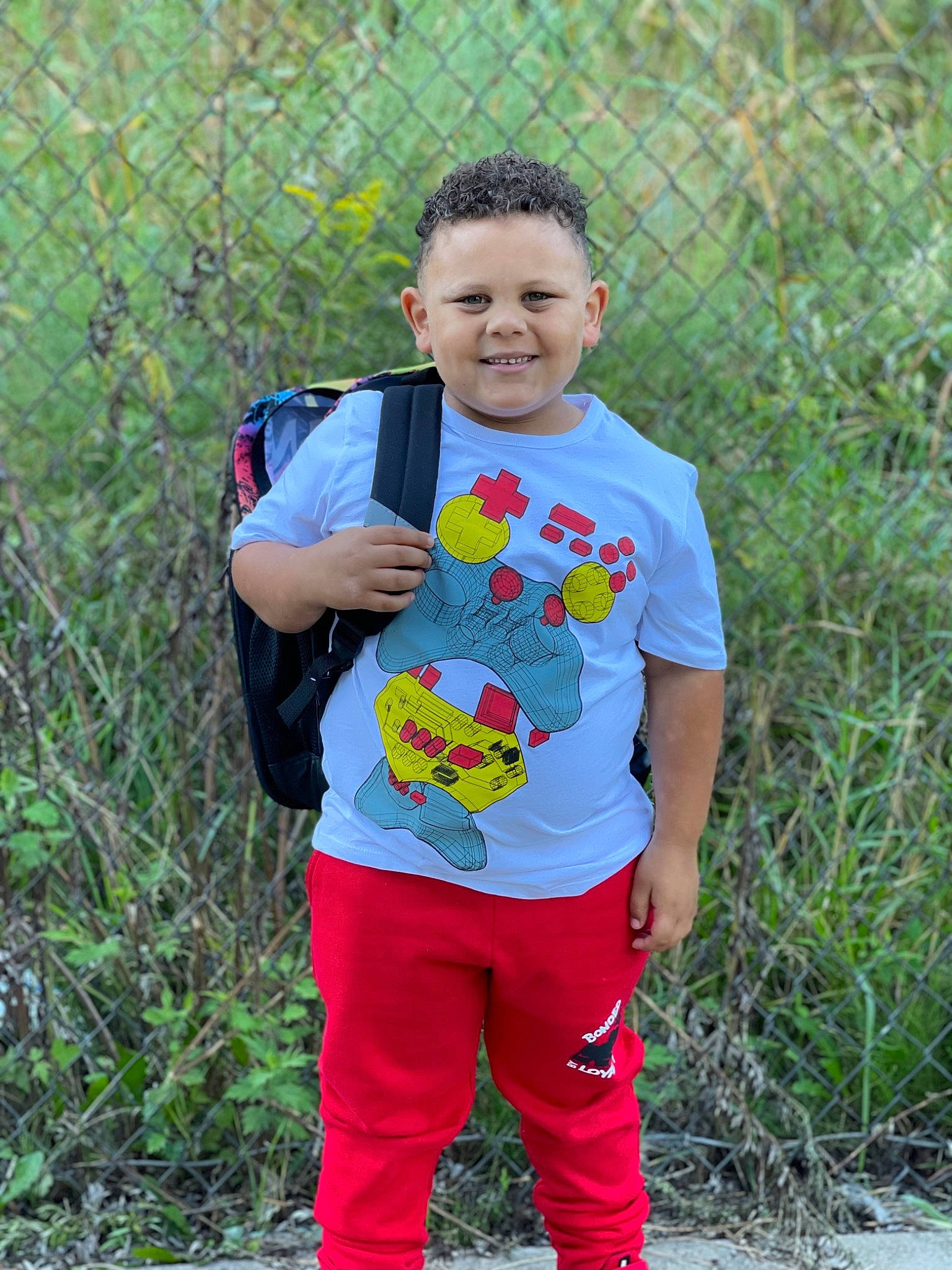 Carter is registered to the contest to win money with this photo: baby_toddler_clothing, child, denim, dress, fence, fun, grass, happy, joy, leisure, magenta, pajamas, pattern, people_in_nature, person, plant, sleeve, smile, street_fashion, t_shirt