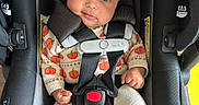 Alaia is registered to the contest to win money with this photo: baby, infant, car_seat, headband, bow, pumpkin_pattern, sweater, knitted_pants, strap, safety_harness, black_car_seat, cute, wide_eyes, smile, indoor, child, person, clothing, footwear, seat