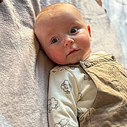 Néo participe au concours pour gagner de l'argent avec cette photo : baby, infant, child, onesie, overalls, sheep_pattern, blanket, face, eyes, head, skin, clothing, soft_light, indoors, portrait, cute, lying_down, expression, young, person