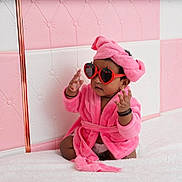 Laya joined the competition — help win amazing prizes! accessories, adorable, baby, child, cute, fashion, headband, indoor, infant, person, pink_robe, pink_wall, playful, portrait, sitting, soft_texture, strawberry_shaped_glasses, sunglasses, tufted_wall, white_surface
