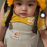 baby, child, yellow_hat, knitted_hat, baby_carrier, floral_shirt, indoor, portrait, person, cute, infant, face, clothing, young_child, closeup, human, expression, headwear, sitting, looking