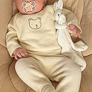 Giorgia a rejoint le concours — aidez-le/la à gagner de superbes lots ! baby, child, pacifier, bow, plush_toy, bunny, cushion, clothing, onesie, footed_pants, infant, seat, beige, cute, portrait, indoor, soft_toy, smiling, relaxed, small_hands