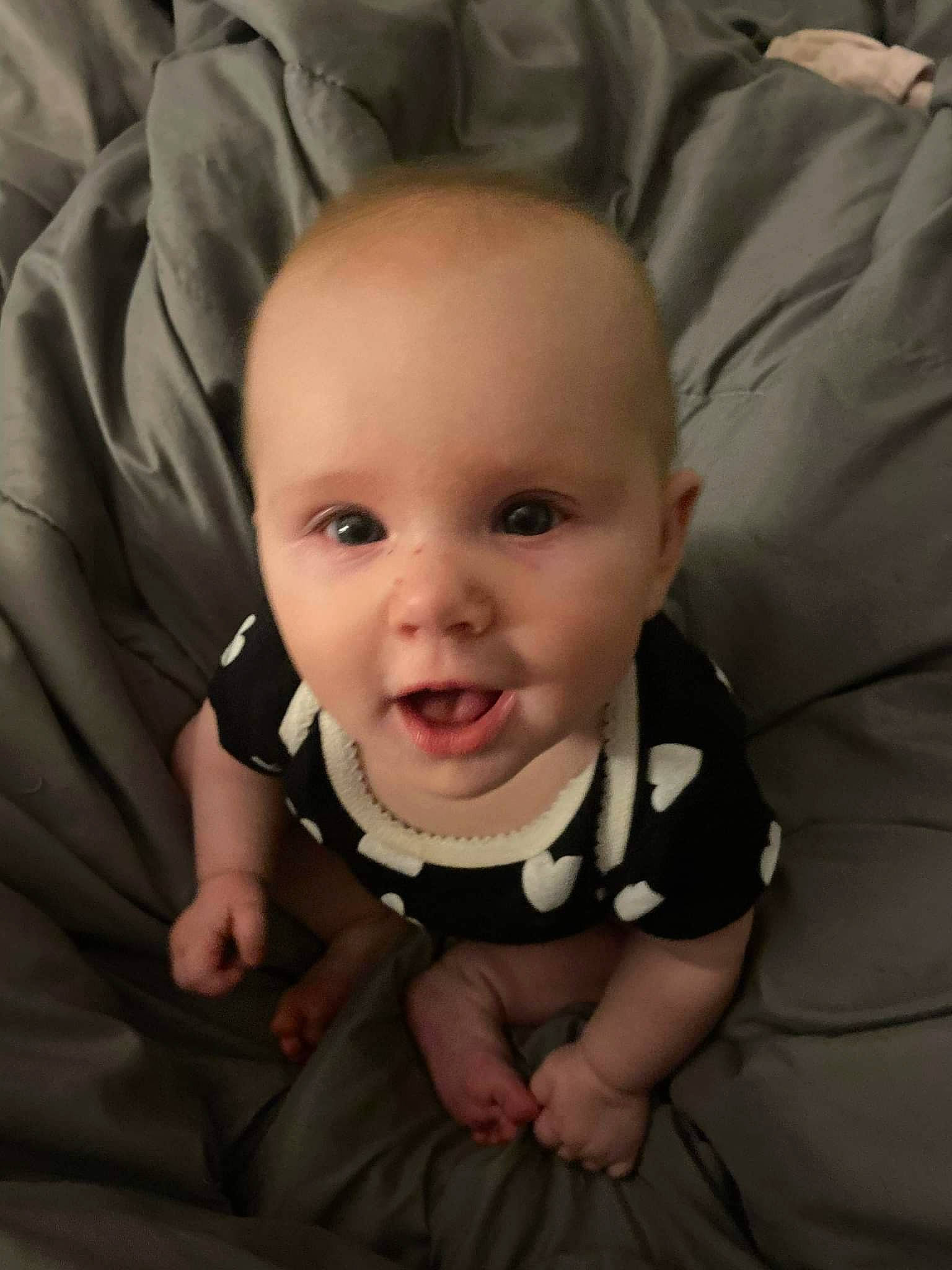 Lilith is registered to the contest to win money with this photo: baby, baby_toddler_clothing, cheek, child, comfort, finger, flash_photography, flooring, gesture, grey, happy, iris, linens, nose, person, sitting, skin, sleeve, smile, toddler