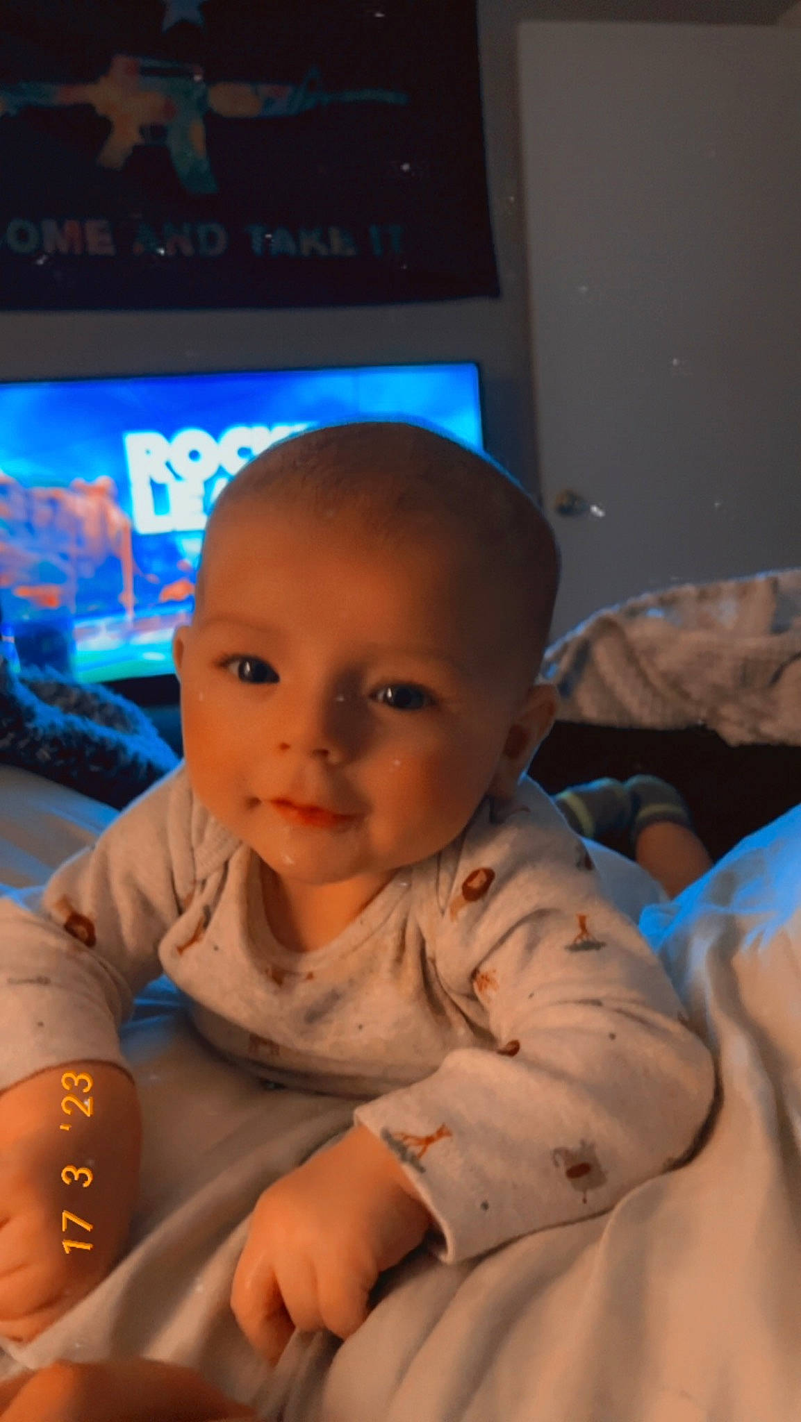 Renly is registered to the contest to win money with this photo: abdomen, audio_equipment, baby, cheek, chest, child, comfort, display_device, flat_panel_display, flooring, fun, gadget, linens, mouth, person, room, sitting, skin, television_set, thumb