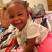 Makiyha is registered to the contest to win money with this photo: toddler, child, smiling, happy, indoor, bedroom, bed, striped_bedspread, pigtails, pink_pants, white_shirt, socks, baby, person, infant, cute, playful, face, hands, home