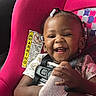 toddler, child, car_seat, smiling, braided_hair, beads, sock, seatbelt, happy, infant, cute, playful, portrait, safety, colorful, pattern, clothing, baby, indoor, seat