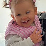 Victoire a rejoint le concours — aidez-le/la à gagner de superbes lots ! toddler, child, smiling, pink_bib, pigtails, white_sweater, indoor, portrait, happy, baby, face, person, home, furniture, couch, hair_bow, cute, hand, young_child, infant