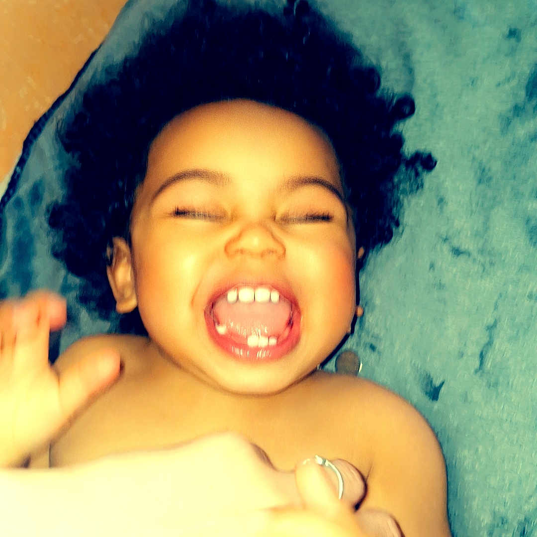 Naylow a rejoint le concours — aidez-le/la à gagner de superbes lots ! baby, blanket, cheerful, child, curly_hair, expression, hands, happy, head, human, indoor, joy, laughing, mouth, person, playful, skin, smile, teeth, toddler