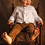 Camille participe au concours pour gagner de l'argent avec cette photo : toddler, child, smiling, barefoot, wooden_chair, white_shirt, brown_pants, indoor, portrait, happy, cute, young, sitting, playful, light, floor, furniture, person, baby, expression