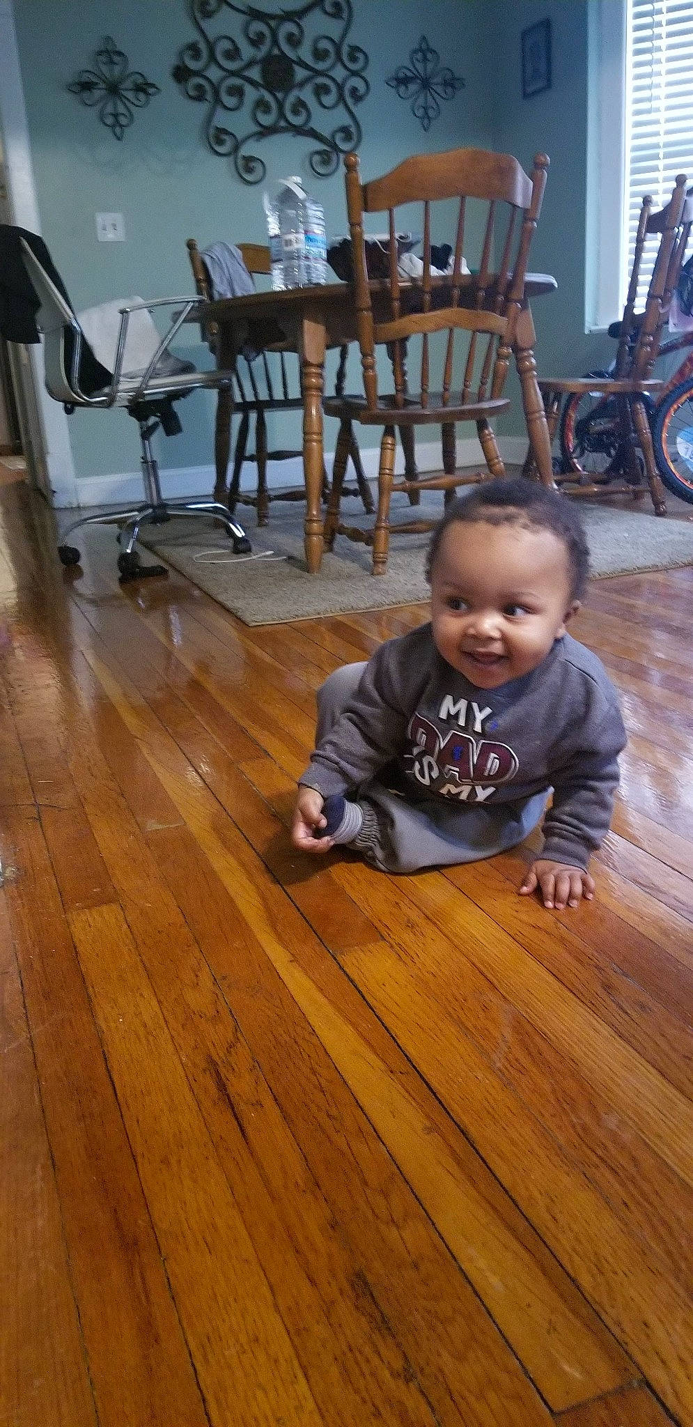 Ahmad is registered to the contest to win money with this photo: baby, baby_toddler_clothing, brown, chair, child, floor, flooring, happy, hardwood, laminate_flooring, person, plank, smile, table, tire, toddler, tree, varnish, wheel, wood