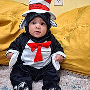 Joey joined the competition — help win amazing prizes! baby, child, infant, cat_in_the_hat, costume, striped_hat, red_hat, bow_tie, black_and_white, sitting, portrait, wide_eyed, indoors, couch, yellow_blanket, carpet, playful, themed_costume, fictional_character, holiday