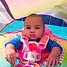 Joey is registered to the contest to win money with this photo: baby, infant, child, portrait, sitting, pool, swimming, float, life_jacket, harness, water, outdoor, summer, colorful, pink, blue, looking_at_camera, serious_expression, close_up, photography
