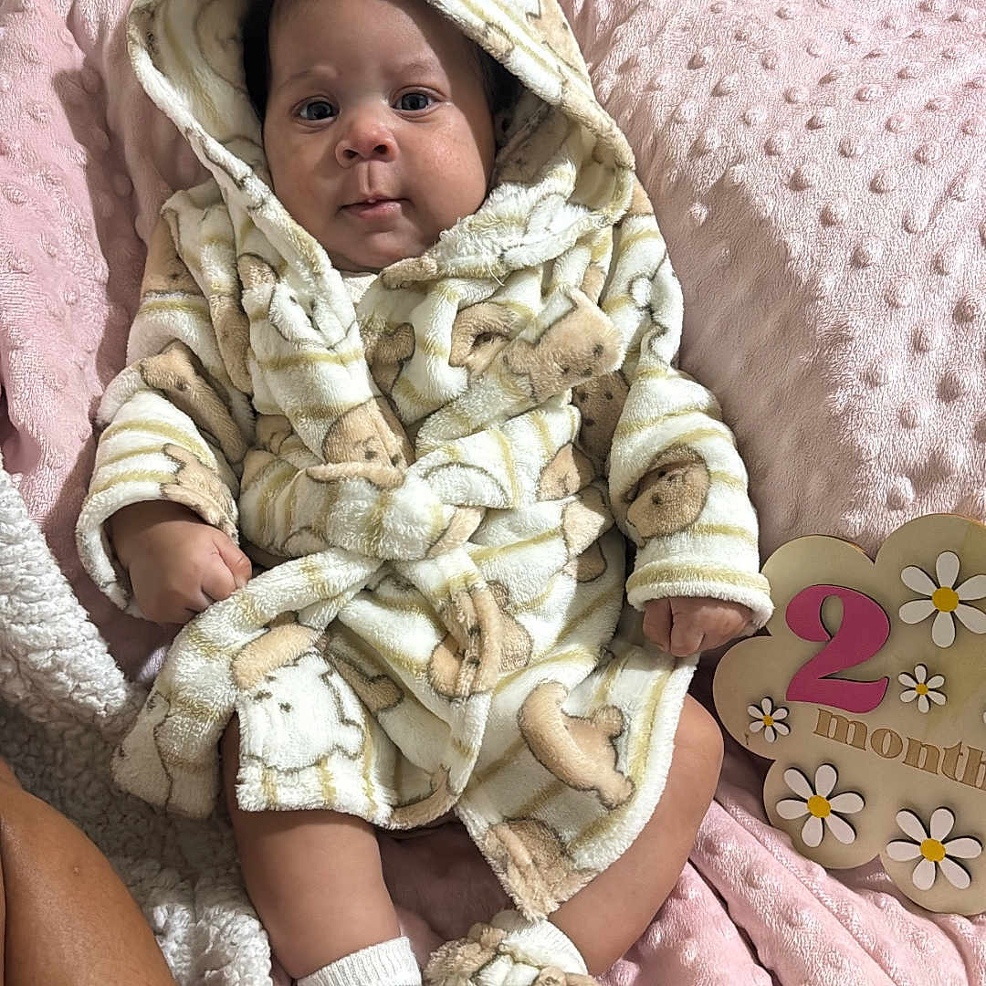 India joined the competition — help win amazing prizes! baby, infant, robe, slippers, blanket, milestone, 2_months, cute, soft_texture, pink, face, person, sitting, indoors, warm_clothing, newborn, child, portrait, hand, cozy