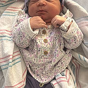 India is registered to the contest to win money with this photo: newborn, baby, infant, blanket, headband, hospital_wristband, sleeping, clothing, purple, floral, cozy, cute, person, indoors, wrapped, soft, resting, child, newborn_clothes, peaceful