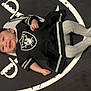 Ezme is registered to the contest to win money with this photo: baby, infant, smile, clothing, black, white, raiders, blanket, tights, lying_down, cute, happy, child, portrait, headwear, patterned_tights, sports_team, logo, indoor, baby_girl