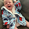 baby, child, smiling, laughing, robe, blue_robe, sports_pattern, couch, furniture, happy, infant, cozy, comfortable, indoor, person, cute, playful, relaxed, seated, portrait