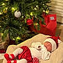 baby, sleeping, christmas_tree, christmas_ornaments, red_hat, red_skirt, white_tights, red_socks, holiday, gift_bag, cozy_blanket, indoor, festive, decorations, holiday_lighting, newborn, cute, sleep, festive_clothing, holiday_season