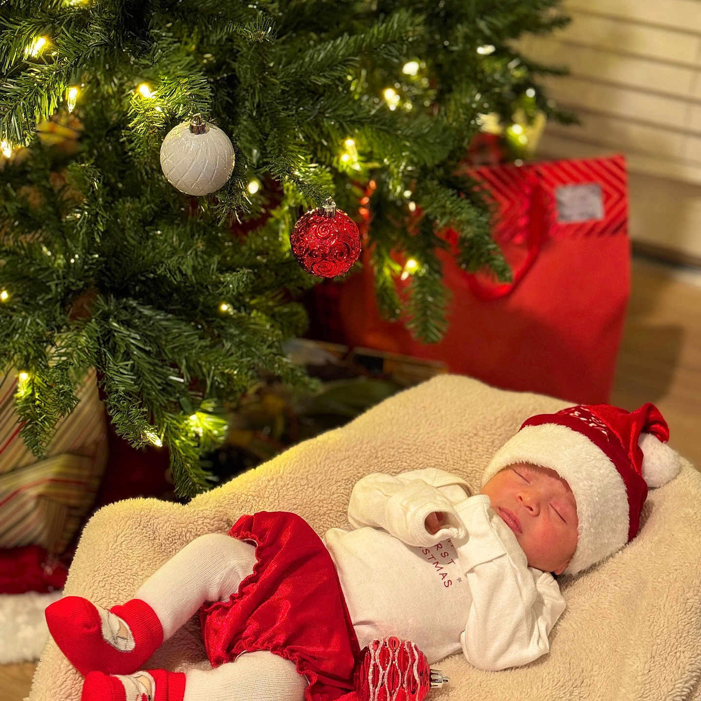 Lia is registered to the contest to win money with this photo: baby, christmas_ornaments, christmas_tree, cozy_blanket, cute, decorations, festive, festive_clothing, gift_bag, holiday, holiday_lighting, holiday_season, indoor, newborn, red_hat, red_skirt, red_socks, sleep, sleeping, white_tights