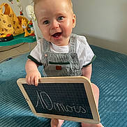 Noham participe au concours pour gagner de l'argent avec cette photo : baby, blue_blanket, chalkboard, child, childhood, cute, face, feet, hand, happy, indoor, infant, overalls, playful, portrait, room, sitting, smiling, toys, white_shirt