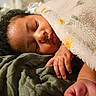Sarai is registered to the contest to win money with this photo: baby, sleeping, blanket, hand, face, curly_hair, cozy, soft_texture, floral_pattern, rest, closeup, infant, peaceful, indoors, warm_light, skin, cute, comfort, portrait, toddler