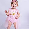 child, toddler, baby, girl, portrait, smiling, happy, birthday, crown, tiara, pink_dress, lace, tutu, shoes, standing, studio, white_background, celebration, one_year_old, photography