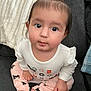 baby, child, infant, girl, sitting, pink_bow, white_shirt, pink_pants, black_cat_prints, couch, indoor, cute, curious_eyes, long_sleeves, barefoot, face, portrait, young_child, home, looking_up