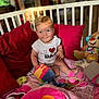 baby, child, crib, toy, plush_toy, cushion, pillow, indoor, smiling, happy, blonde_hair, blue_eyes, shirt, sitting, colorful, soft_toys, playtime, cute, person, home