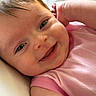 Kennedy is registered to the contest to win money with this photo: baby, smiling, close_up, face, pink_clothing, infant, joyful, happy, skin, head, eyes, mouth, arm, cheeks, lying_down, child, cute, person, indoors, portrait