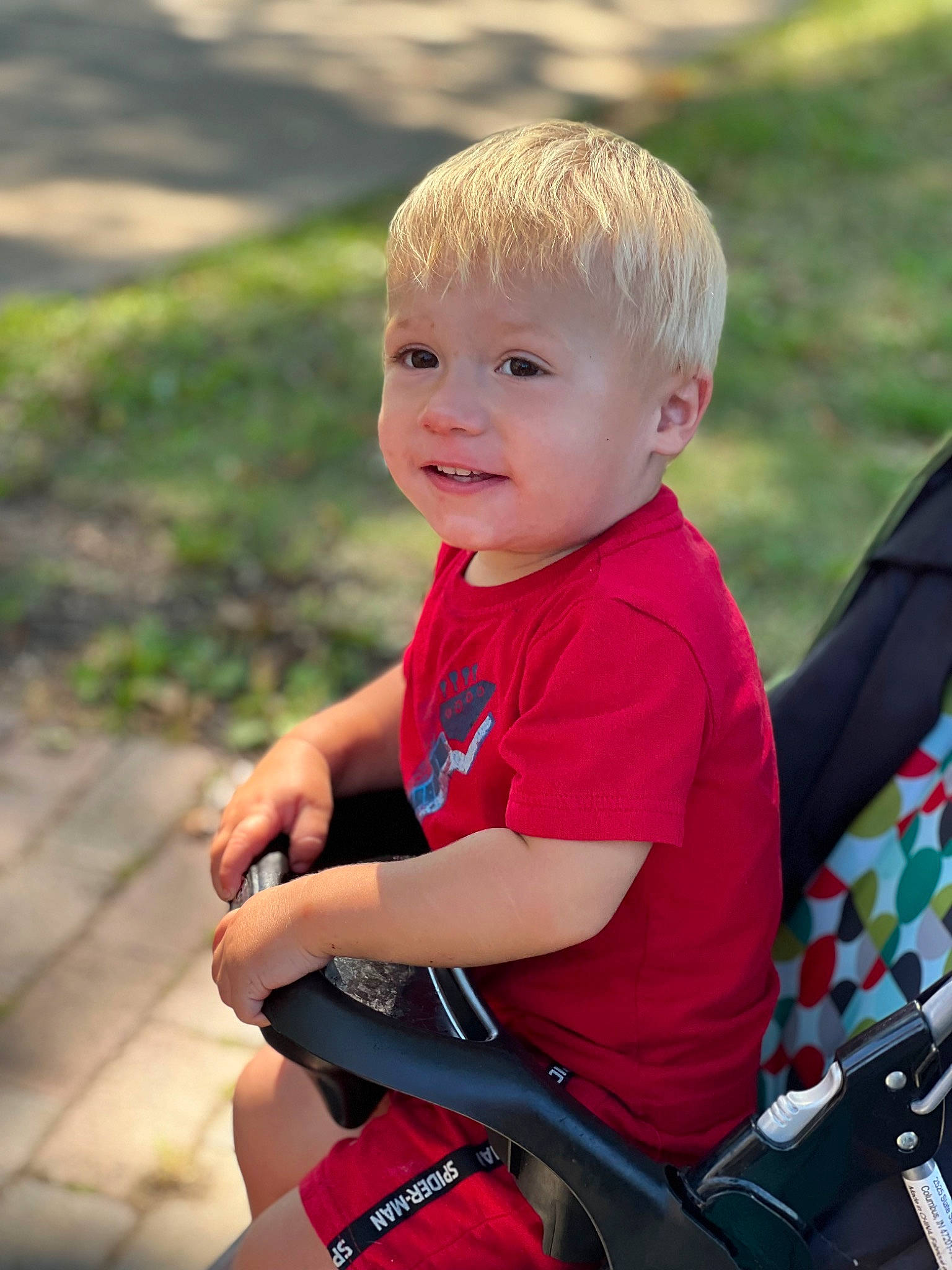 Bryson is registered to the contest to win money with this photo: baby_carriage, baby_products, baby_toddler_clothing, child, eye, face, fun, grass, happy, head, leisure, people_in_nature, person, recreation, shorts, sitting, skin, smile, t_shirt, toddler