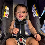 Winston joined the competition — help win amazing prizes! baby, car_seat, child, smiling, harness, striped_clothing, sitting, happy, indoors, infant, cute, face, person, seatbelt, safety, young_child, cheerful, human, skin, portrait