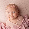 baby, infant, pink, headband, bow, wrapped, blanket, soft_fabric, portrait, blue_eyes, face, cute, child, newborn, lying_down, pastel, patterned_background, closeup, skin, peaceful