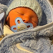 Issac is registered to the contest to win money with this photo: newborn, baby, sleeping, pacifier, hat, knitted, blue, jacket, fuzzy, cozy, infant, cute, closeup, portrait, child, warm, resting, soft, indoors, peaceful