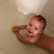 Alita is registered to the contest to win money with this photo: baby, child, bathtub, bath_time, smiling, happy, wet_hair, blue_eyes, infant, portrait, close_up, water, bath_foam, yellow_toy, indoor, home, skin, sitting, playful, photography