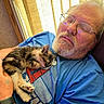 Marley is registered to the contest to win money with this photo: man, cat, kitten, calico, sleeping, glasses, beard, blue_shirt, indoor, window, blinds, sunlight, couch, cuddling, pet, furry, relaxed, portrait, arms, wristband