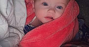 Ryleigh joined the competition — help win amazing prizes! baby, infant, child, face, eyes, wide_eyed, blanket, coral_blanket, bedding, bed, cozy, indoors, portrait, close_up, sitting, lying_down, plaid_fabric, textile, home, cute
