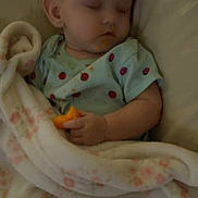 Ryleigh is registered to the contest to win money with this photo: baby, infant, sleeping, bed, blanket, pajamas, ladybug_pattern, snack, orange_food, cuddled, cozy, indoors, bedroom, portrait, face, eyes_closed, sitting, resting, soft_blanket, nap
