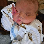 Judah is registered to the contest to win money with this photo: baby, newborn, sleeping, infant, teddy_bear, white_clothing, cute, peaceful, hand, face, cozy, soft, portrait, child, person, indoors, cute_outfit, resting, closeup, adorable