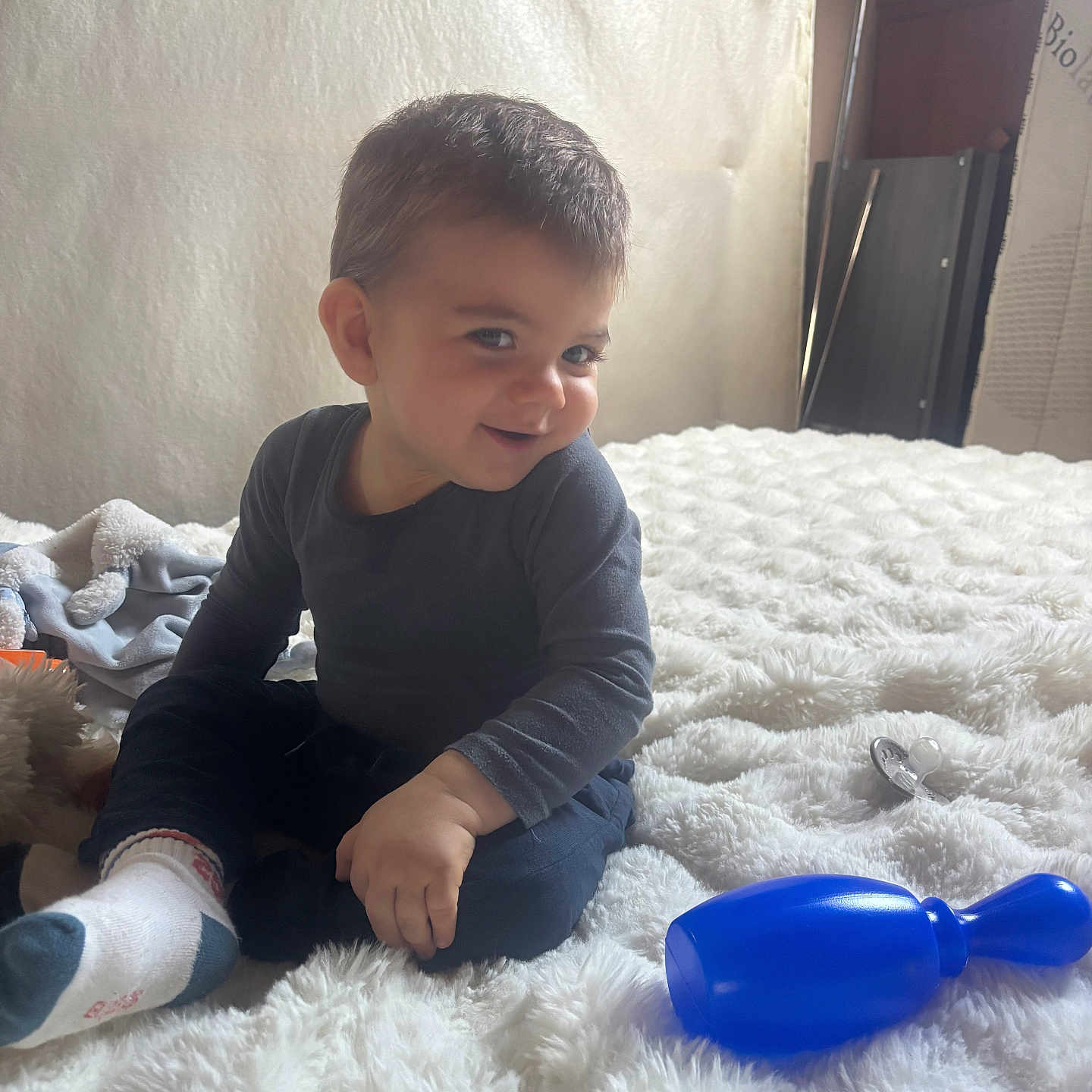 Elyano a rejoint le concours — aidez-le/la à gagner de superbes lots ! toddler, child, smiling, indoor, blanket, toy, pacifier, rattle, furniture, bed, cozy, happy, sitting, person, clothing, sock, hair, face, cute, home
