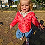toddler, child, outdoor, smiling, red_jacket, polka_dot, denim_skirt, sunlight, pavement, shoes, happy, cute, person, face, young_child, playful, daylight, nature, fence, blue_sky