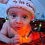 baby, infant, christmas_hat, holiday_lights, red_blanket, close_up, face, eyes, hands, indoors, festive, newborn, cute, expression, warm_lighting, celebration, child, portrait, holiday, seasonal