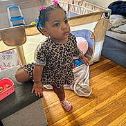 Olivia Joyner is registered to the contest to win money with this photo: balancing, child, couch, curious, dress, floor, furniture, hair_beads, home, indoor, leopard_print, living_room, person, plastic_toy, playpen, sock, toddler, toy, window, wooden_floor
