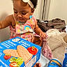 Olivia Joyner joined the competition — help win amazing prizes! baby, baby_food, bed, blanket, box, child, colorful_clothing, curious, food, foot, hand, headband, indoor, person, product_packaging, room, sitting, snacks, table, toddler