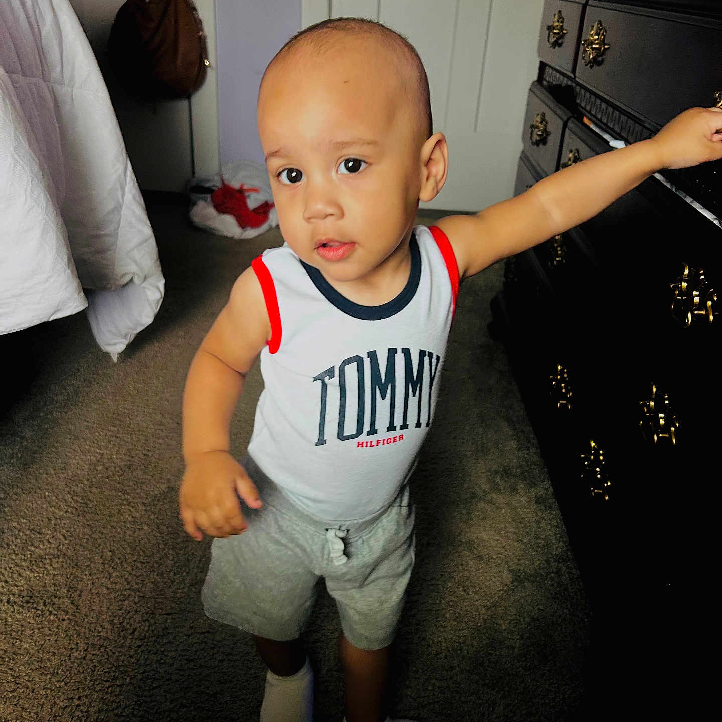 Makaius joined the competition — help win amazing prizes! bag, bedroom, carpet, casual, child, clothing, curious, door, dresser, face, floor, furniture, hand, indoor, person, shorts, socks, standing, tank_top, toddler