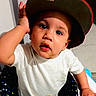 baby, cap, child, clothing, curious, cute, expression, face, hand, hat, indoor, looking_up, person, polka_dot, portrait, seat, sitting, toddler, white_shirt, young_child