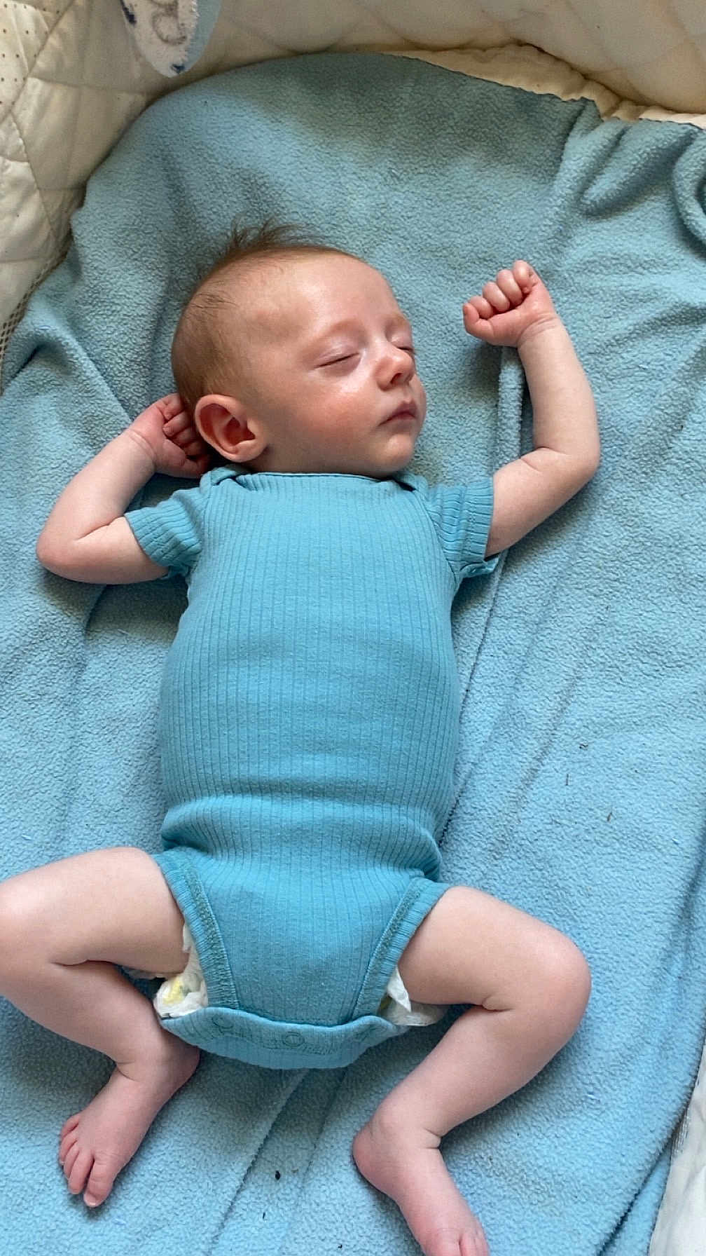 Westyn is registered to the contest to win money with this photo: baby, sleeping, blue_onesie, blanket, infant, peaceful, arms_up, legs_spread, soft_texture, indoor, child, cute, resting, newborn, skin, head, foot, hand, clothing, portrait
