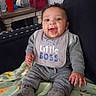baby, bag, bib, blanket, child, cozy, cute, face, footwear, furniture, gray_clothing, happy, indoor, person, portrait, red_cup, sitting, smiling, table, water_bottle