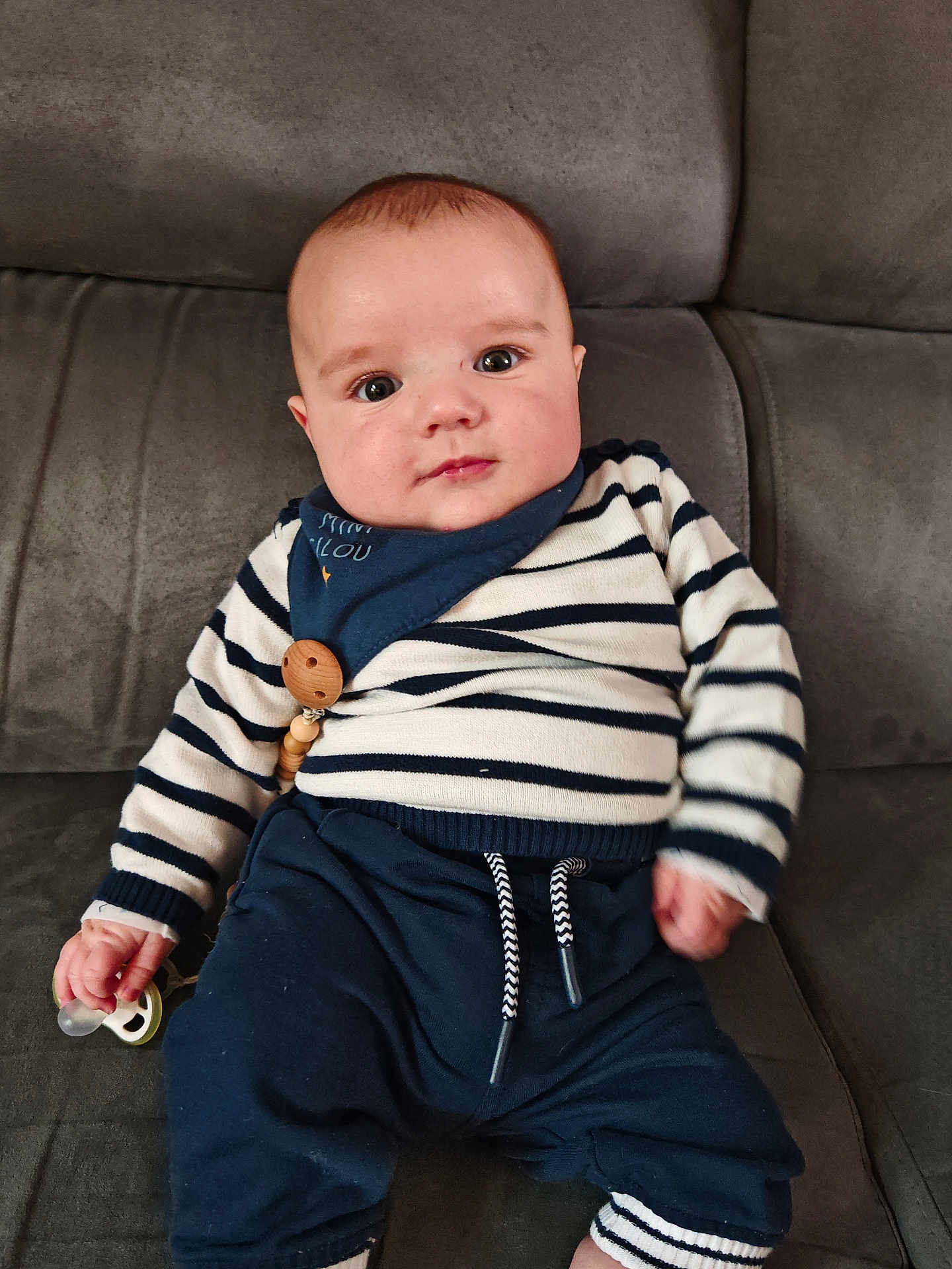 Néo a rejoint le concours — aidez-le/la à gagner de superbes lots ! baby, infant, striped_clothing, pacifier, couch, seated, blue_pants, face, child, indoor, home, comfort, cute, young, person, soft_furniture, casual_clothing, expression, small_hand, babysitting