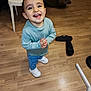 Teïva a rejoint le concours — aidez-le/la à gagner de superbes lots ! child, toddler, smiling, happy, standing, light_blue_sweater, jeans, white_shoes, wooden_floor, indoor, chair, slippers, staircase, person, floor, home, cute, casual_clothing, young_child, looking_up
