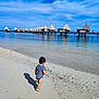 toddler, beach, sand, water, ocean, sky, clouds, pier, bungalows, vacation, summer, child, swimsuit, shadow, outdoor, nature, travel, holiday, coast, shore