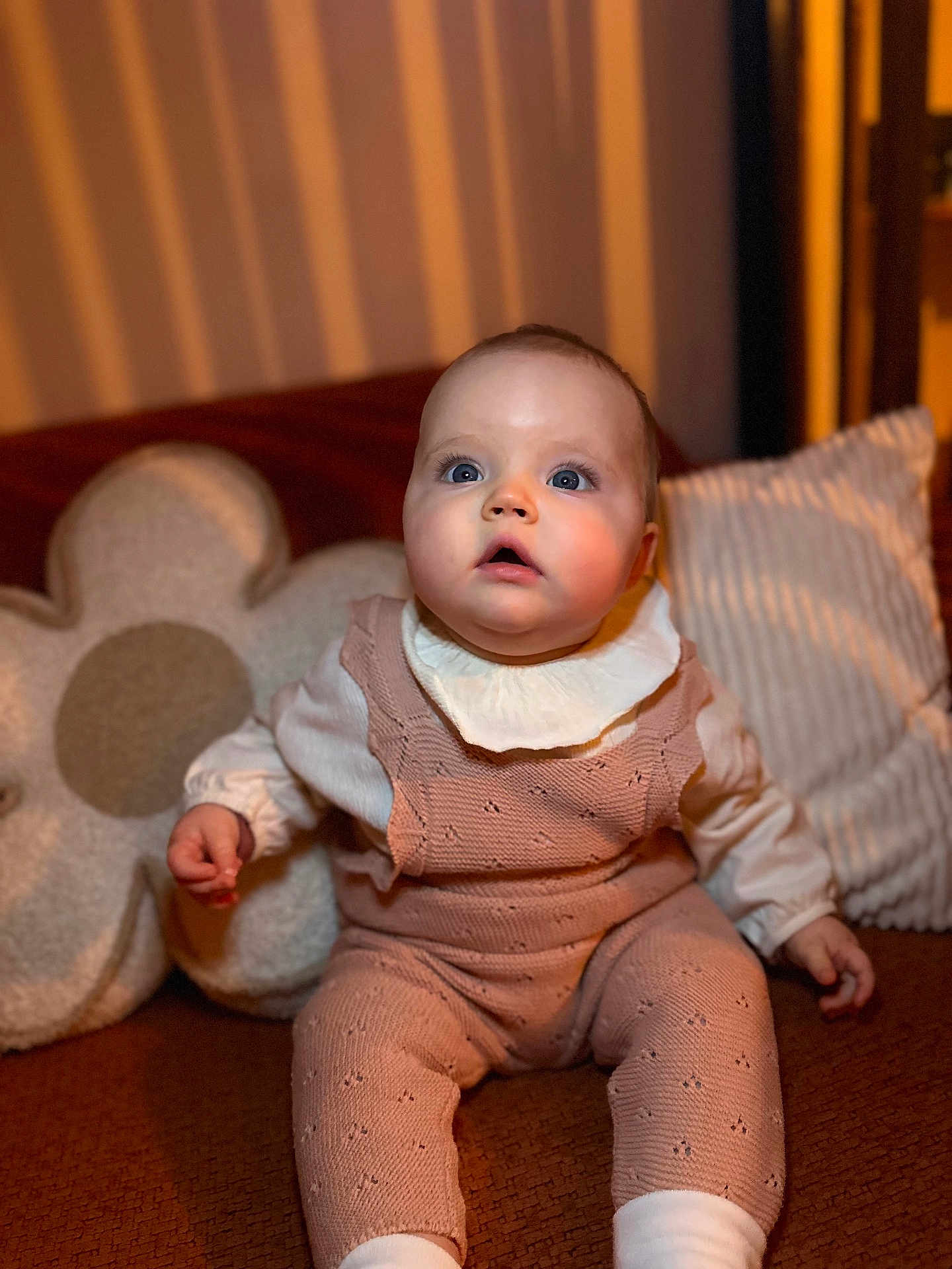 Abby a rejoint le concours — aidez-le/la à gagner de superbes lots ! baby, infant, child, couch, pillow, flower_pillow, knitwear, pink_outfit, white_collar, blue_eyes, indoor, portrait, sitting, soft_lighting, curious_expression, cozy, home_interior, warm_colors, furniture, cute